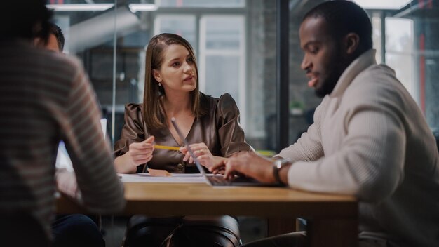 Photo young creative team meeting with business partners in conference room behind glass walls in agency colleagues sit behind conference table and discuss business opportunities growth and development