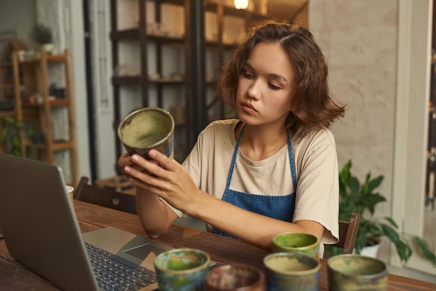 Young creative woman holding selfmade clay mug