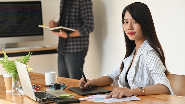 Young creative woman looking at camera on creativity workplace.