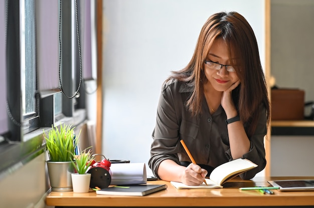 Young creative woman sketching on notebook on table.