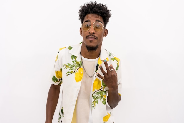 A young Cuban man in a floral shirt and glasses smiling and dancing on a white background, copy and paste space