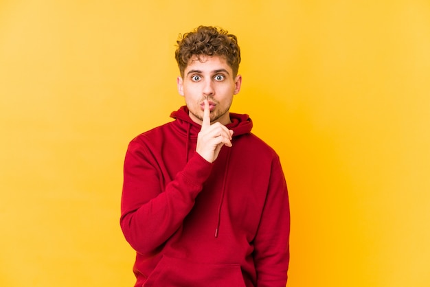 young curly blond man doing a silence gesture