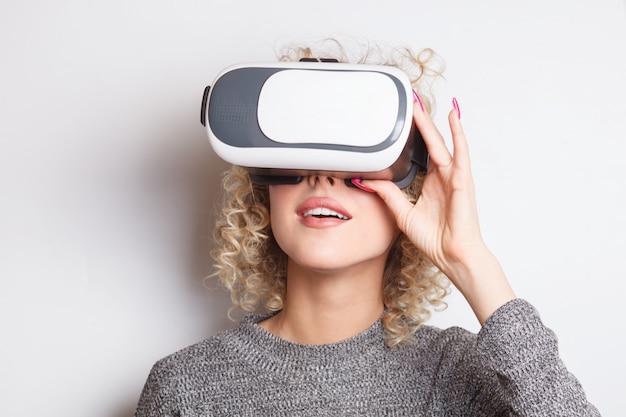 Young curly blonde woman in VR glasses