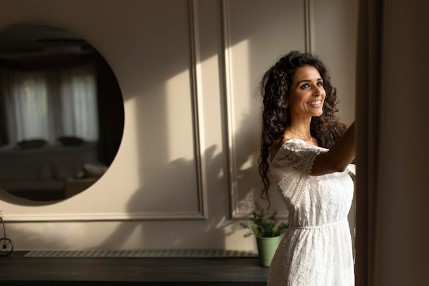 Young curly hair woman standing by the window in the room