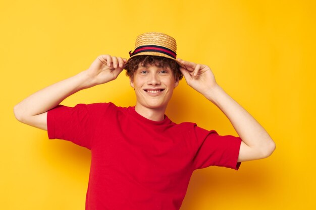 Young curly-haired man emotions red t-shirt hat studio yellow background unaltered person