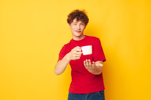 Young curly-haired man posing with a white mug and in the hands of a drink lifestyle unaltered person