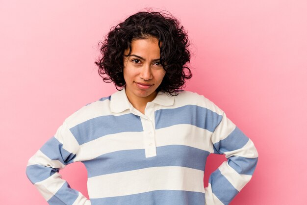 Photo young curly latin woman isolated on pink background blows cheeks, has tired expression. facial expression concept.