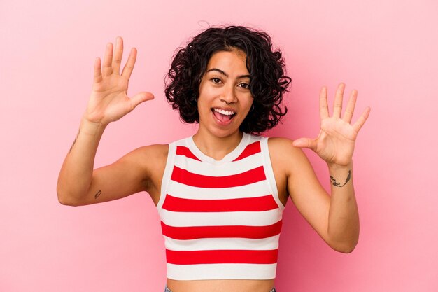 Foto giovane donna latina riccia isolata su sfondo rosa che celebra una vittoria o un successo, è sorpreso e scioccato.