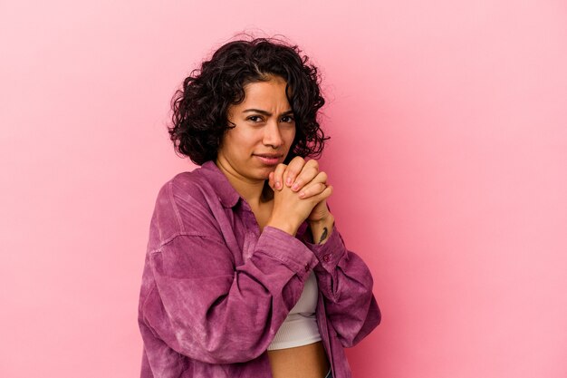 Young curly latin woman isolated on pink background scared and afraid.