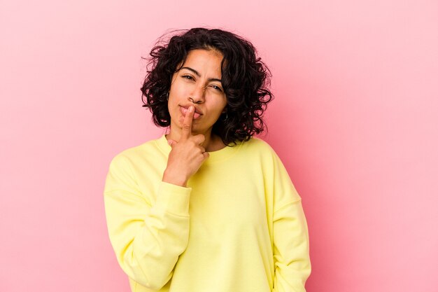 Young curly latin woman isolated on pink background thinking and looking up, being reflective, contemplating, having a fantasy.