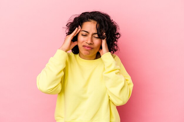 Young curly latin woman isolated on pink background touching temples and having headache.