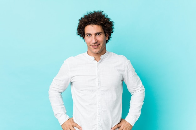 Young curly mature man wearing an elegant shirt confident keeping hands on hips