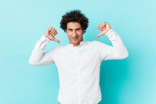 Young curly mature man wearing an elegant shirt feels proud and self confident, example to follow.