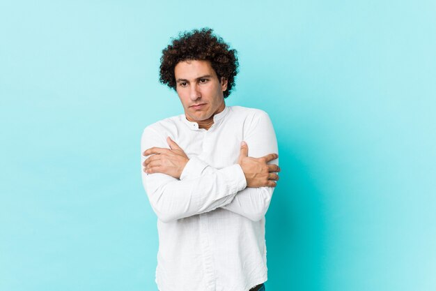 Young curly mature man wearing an elegant shirt going cold due to low temperature