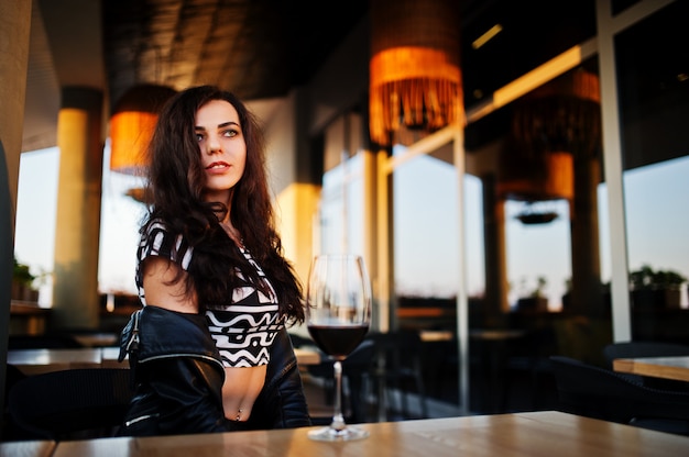 Young curly woman enjoying  her wine in a bar.