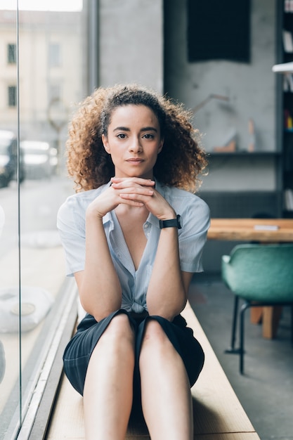 Young curly woman sitting and looking camera