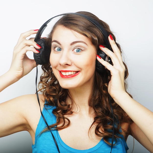 Young curly woman with headphones listening music.Studio shot.