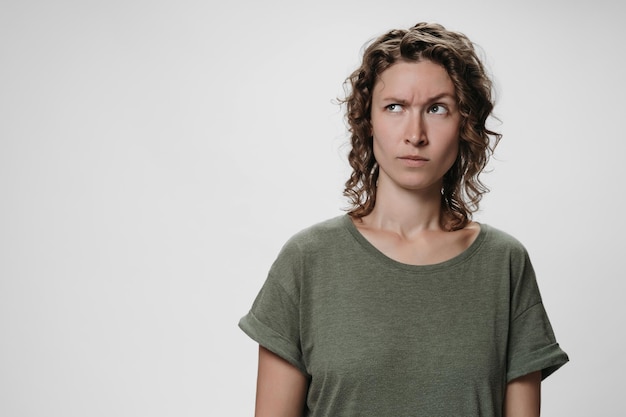 Photo young curly woman with puzzled raises eyebrows negative facial expression