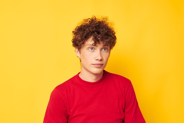 若い縮れ毛の男赤いTシャツ楽しいポーズカジュアルウェア黄色の背景変更なし