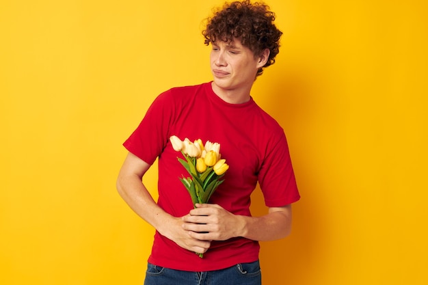 赤いTシャツを着た若い縮れ毛の男花の花束ホリデーギフトライフスタイルは変更されていません