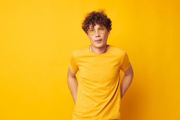 Young curlyhaired man wearing stylish glasses yellow tshirt posing monochrome shot