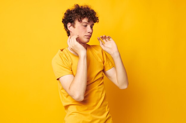 Young curlyhaired man yellow tshirt fashion hand gestures isolated background unaltered