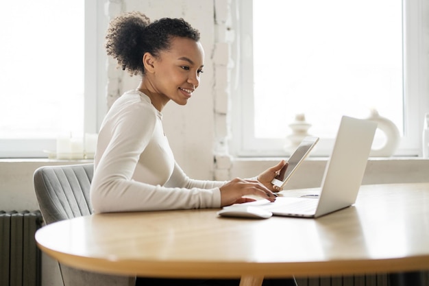 Un giovane studente in linea dai capelli ricci che utilizza un computer portatile dell'ufficio comunicazione video affascinante dello studente