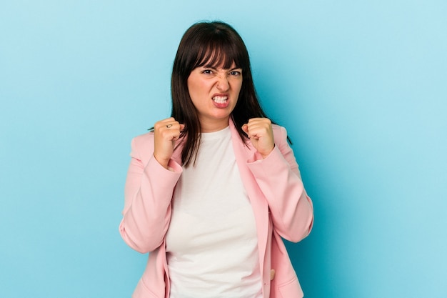 Young curvy caucasian woman isolated on blue background upset screaming with tense hands.