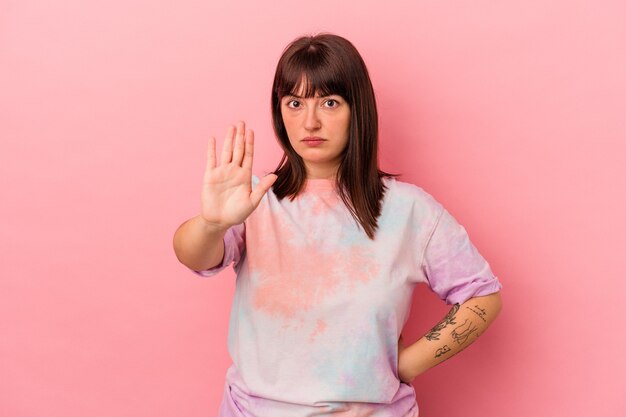 Young curvy caucasian woman isolated on pink background being shocked due to an imminent danger