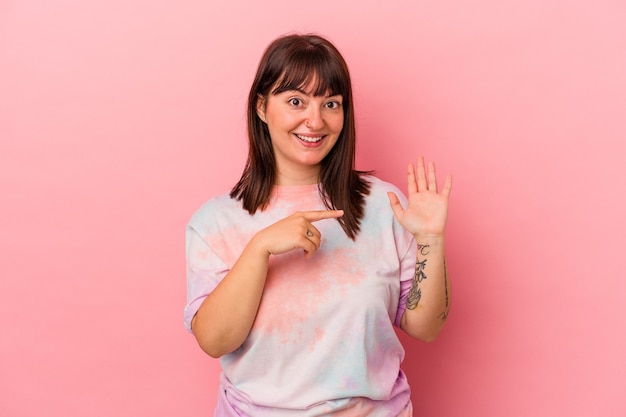 Young curvy caucasian woman isolated on pink background smiling cheerful showing number five with fingers.