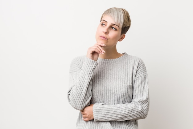 Young curvy caucasian woman isolated white  looking sideways with doubtful and skeptical expression.