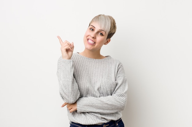 Young curvy caucasian woman isolated on white  smiling cheerfully pointing with forefinger away.