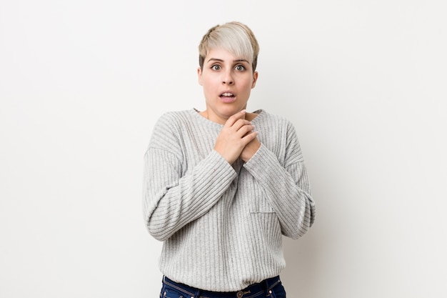 Young curvy caucasian woman isolated on white wall scared and afraid.