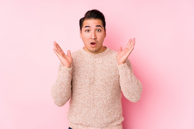 Young curvy man posing in a pink wall isolated surprised and shocked.