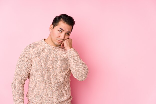 Young curvy man posing in a pink wall isolated who feels sad and pensive, looking at copy space.