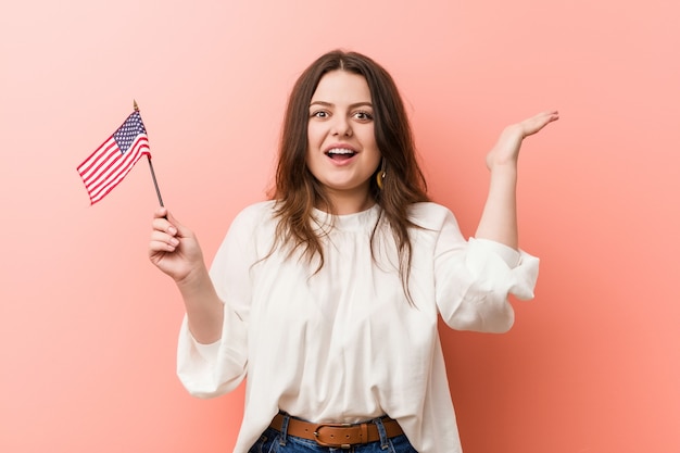 Young curvy plus size woman holding a united states flag celebrating a victory or success