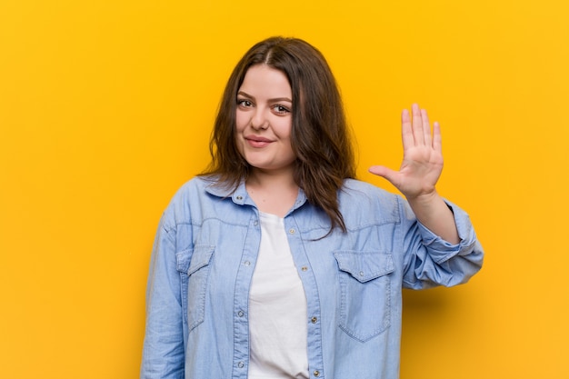 Young curvy plus size woman smiling cheerful showing number five with fingers.