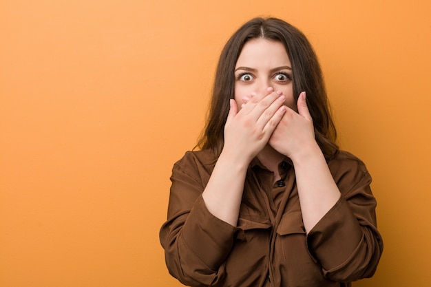 Young curvy russian woman shocked covering mouth with hands.