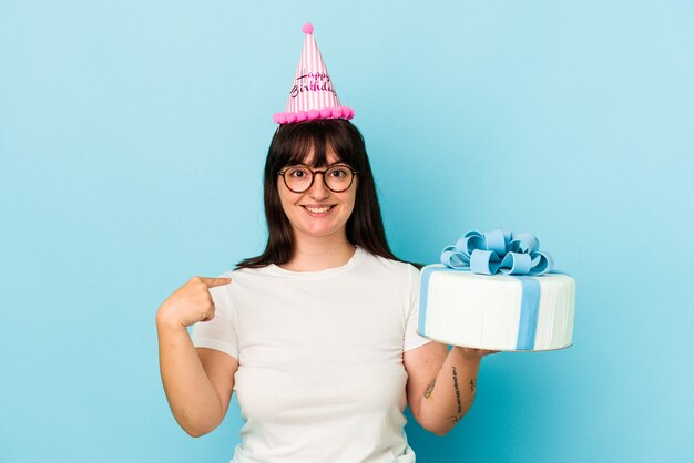 Young curvy woman celebrating her birthday isolated on blue background person pointing by hand to a shirt copy space, proud and confident