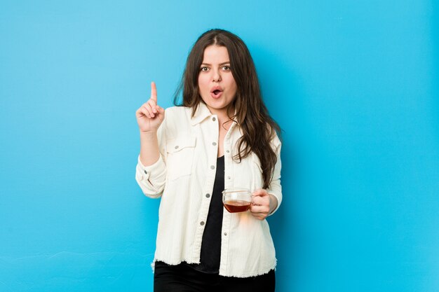 Young curvy woman holding a tea cup having some great idea, concept of creativity.