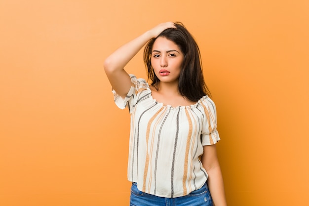 Young curvy woman tired and very sleepy keeping hand on head.