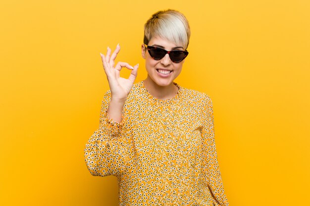 Young curvy woman wearing a floral summer clothes cheerful and confident showing ok gesture