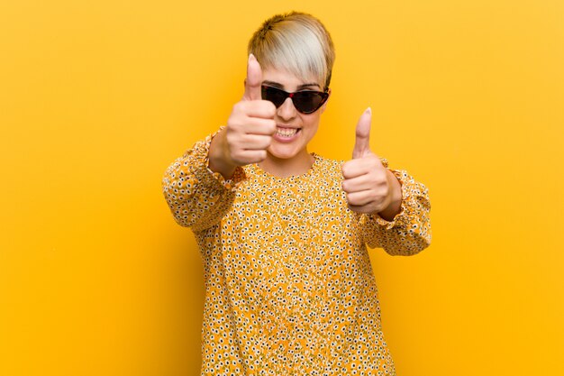 Young curvy woman wearing a floral summer clothes with thumbs ups, cheers about something