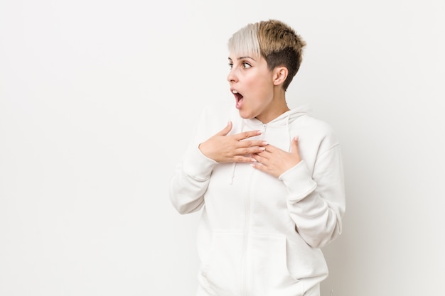 Young curvy woman wearing a white hoodie being shocked because of something she has seen.