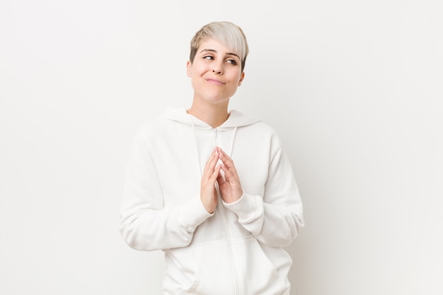 Young curvy woman wearing a white hoodie making up plan in mind, setting up an idea