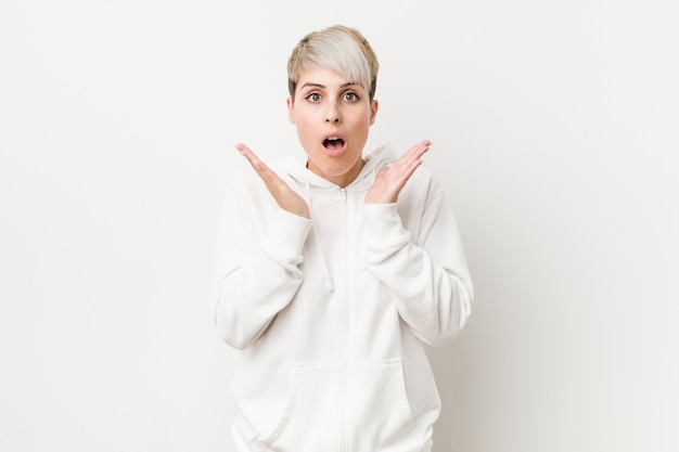 Young curvy woman wearing a white hoodie surprised and shocked.