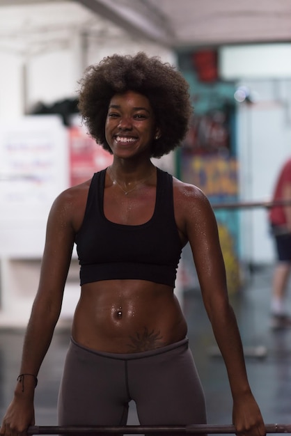 Photo young cute african american sport woman in fitness room lifting empty bar