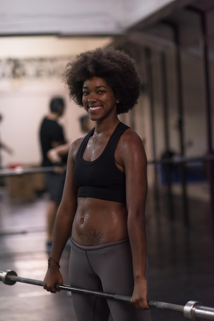 Young Cute african american sport woman in fitness room lifting empty bar