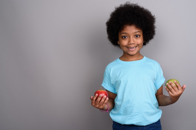 Young cute African girl against gray wall