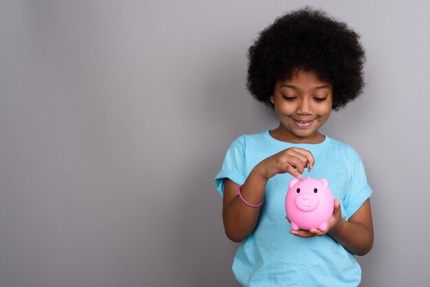 Young cute African girl against gray wall